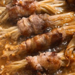 enoki beef rolls simmering in sauce in a skillet