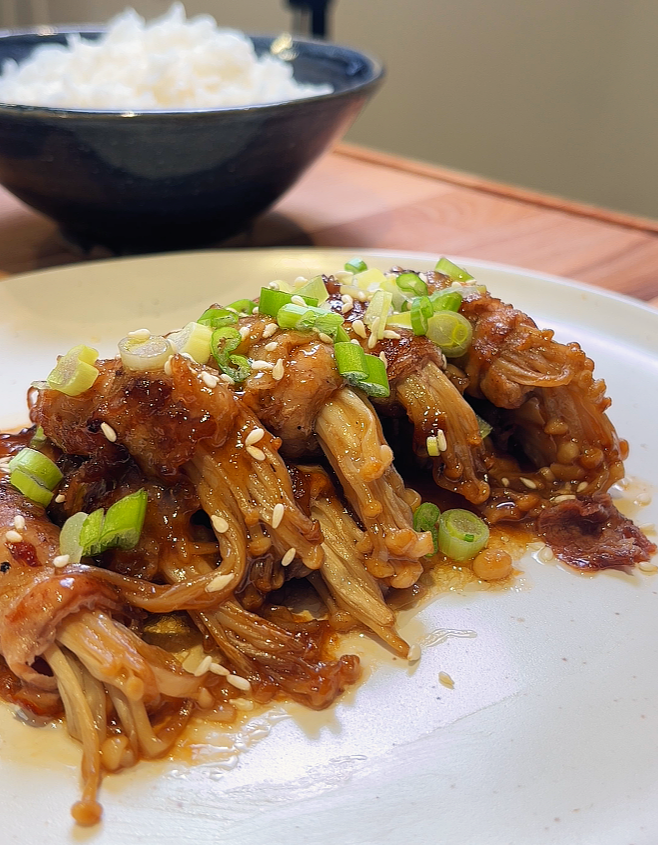 enoki beef rolls served on plate drizzled with sauce